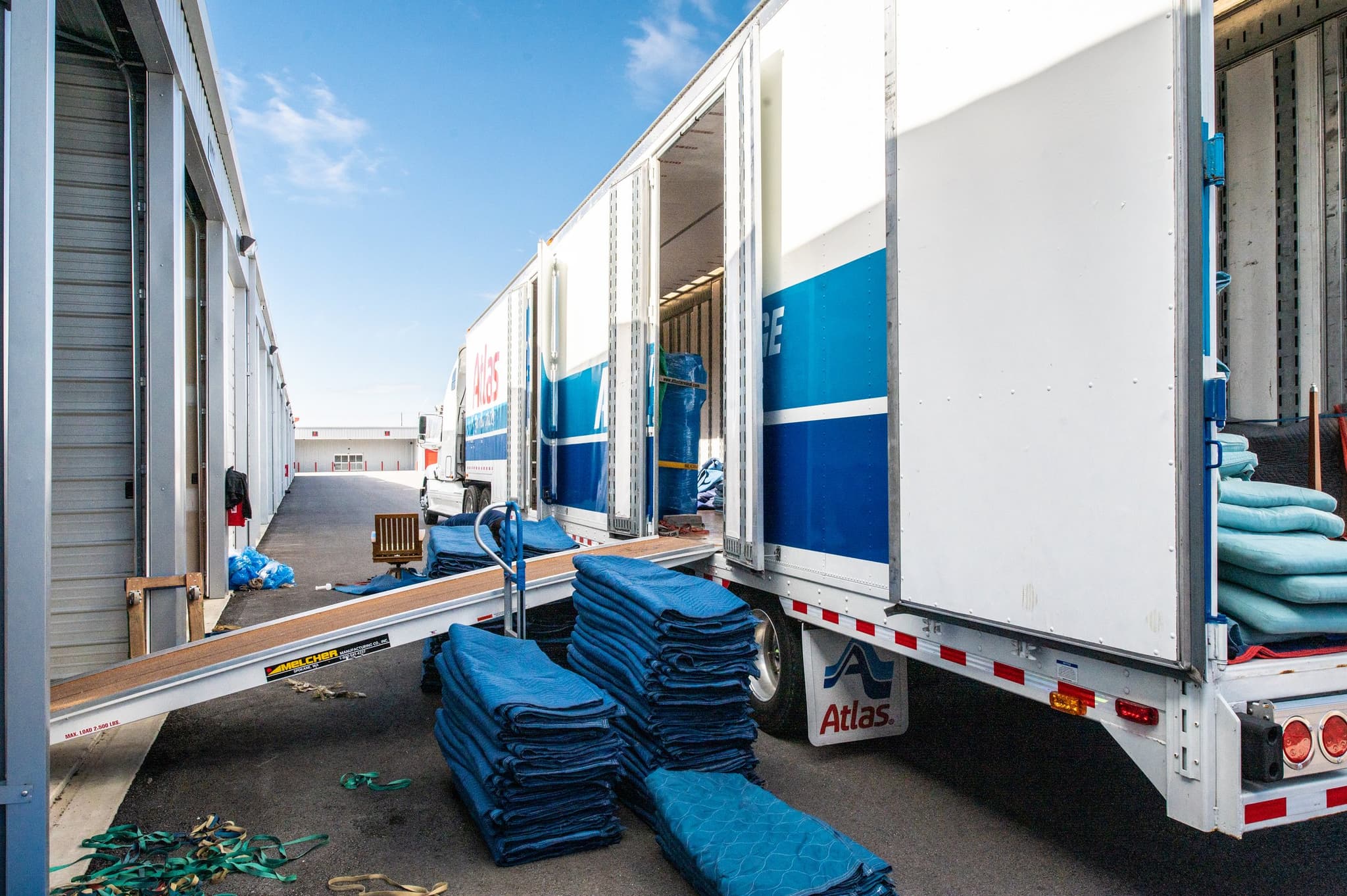 Atlas moving trucks backed into Modern Storage® with loading ramps and moving blankets prepared for business storage